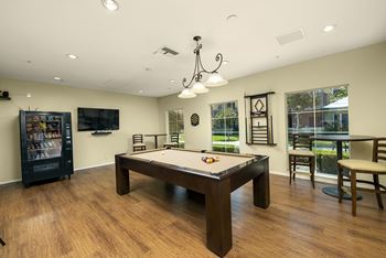 A room with a pool table and a vending machine.